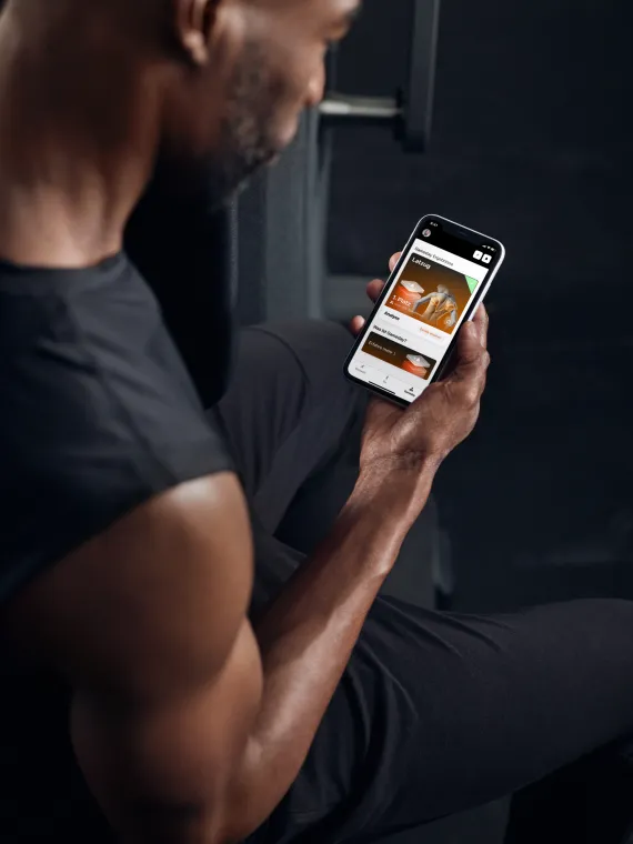 Image of woman holding a cell phone looking at the EGYM member app